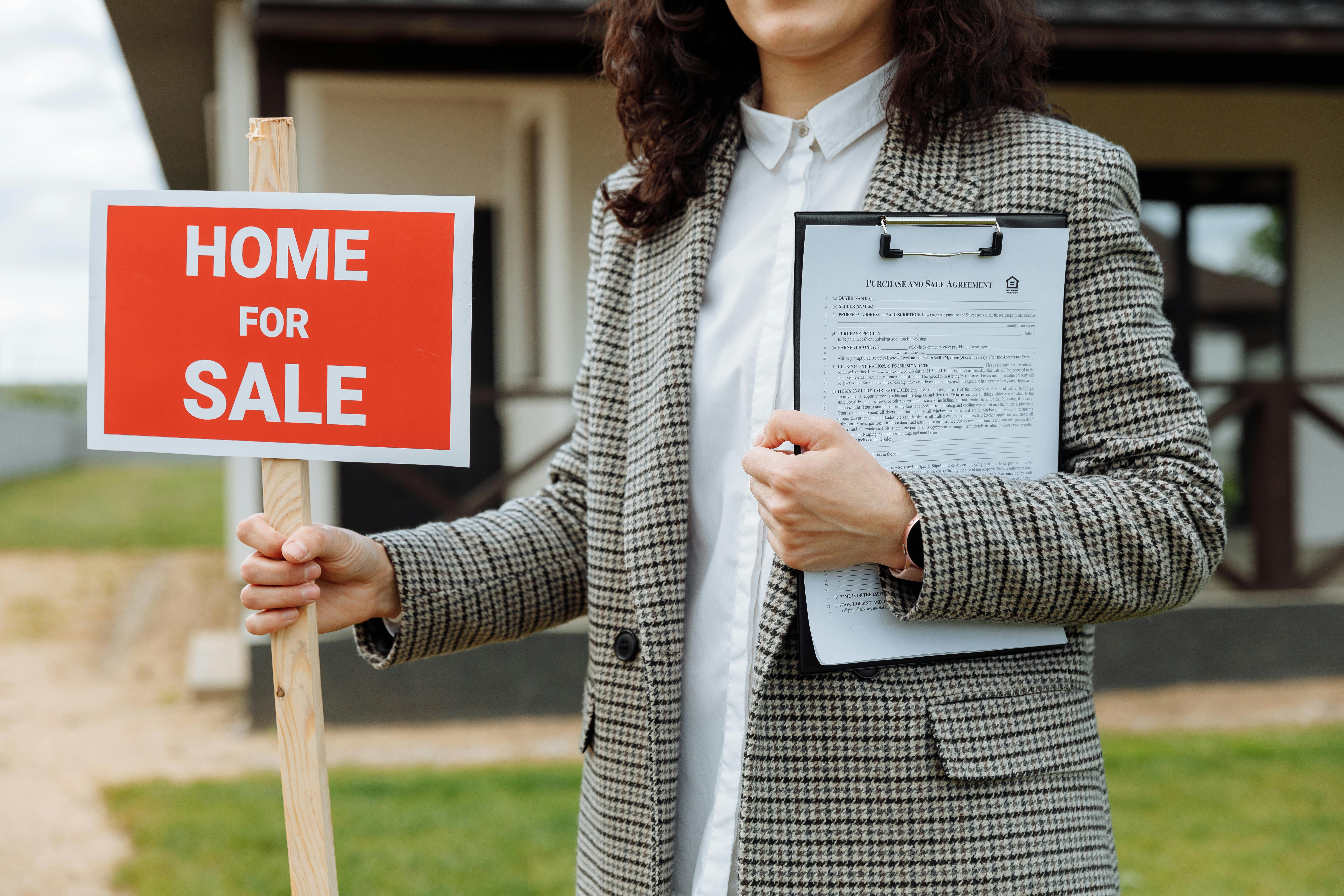 person%20holding%20'home%20for%20sale'%20sign